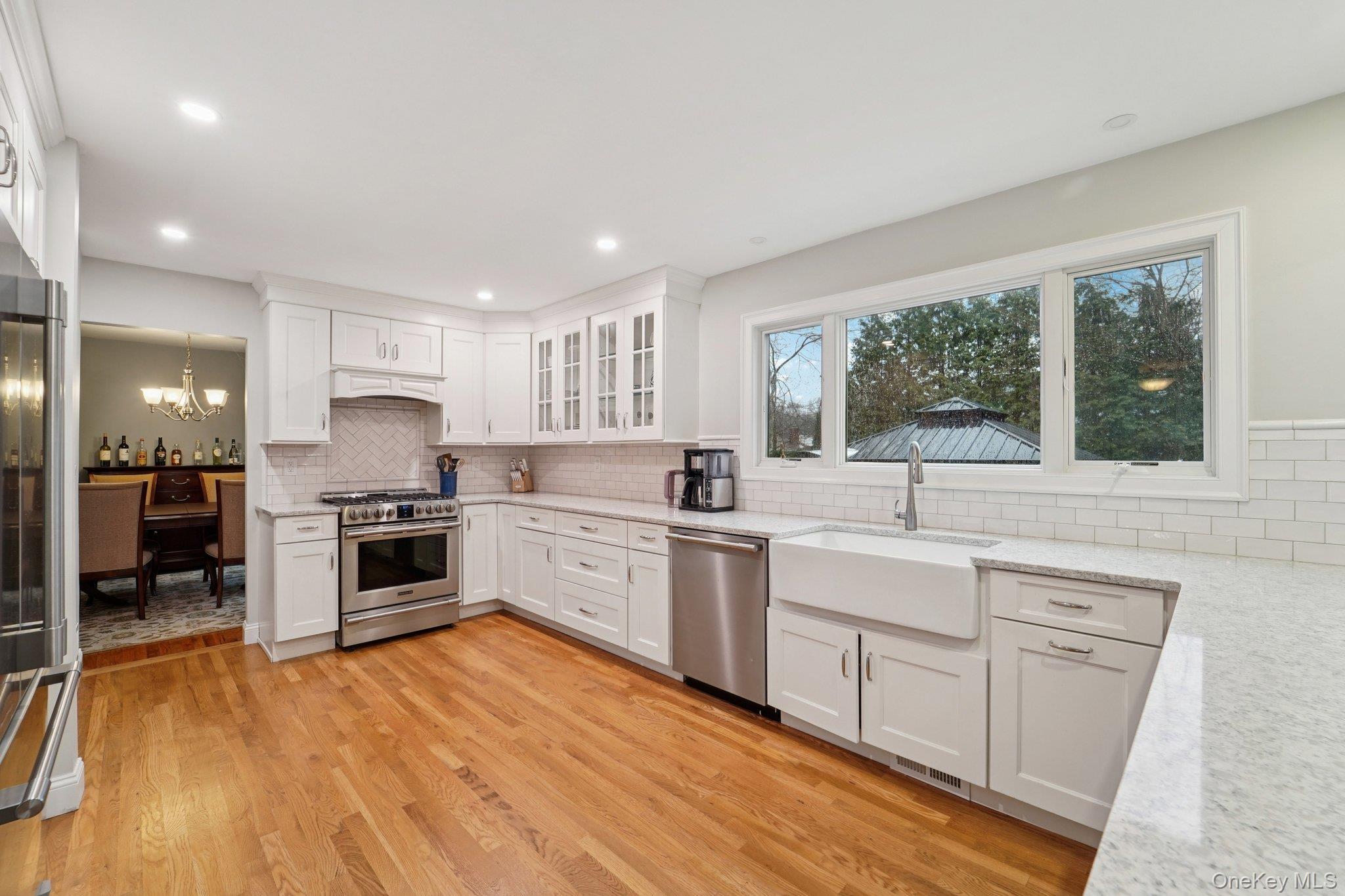 84 Townline Road Nanuet, NY 10954 - Photo 6 of 44 Kitchen with appliances with stainless steel finishes, white cabinets, light stone countertops, a chandelier, and glass insert cabinets