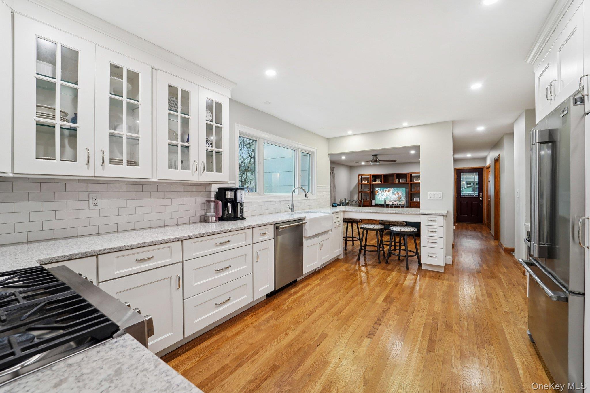 84 Townline Road Nanuet, NY 10954 - Photo 7 of 44 Kitchen featuring white cabinetry, light stone counters, a kitchen bar, stainless steel appliances, and light wood-style floors