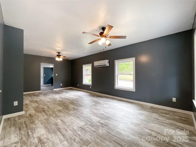 a view of a big room with windows and ceiling fan