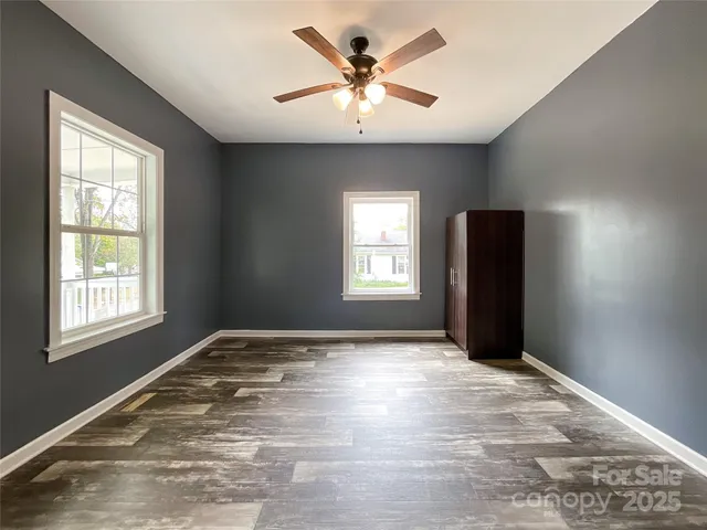 a view of an empty room with window and a kitchen