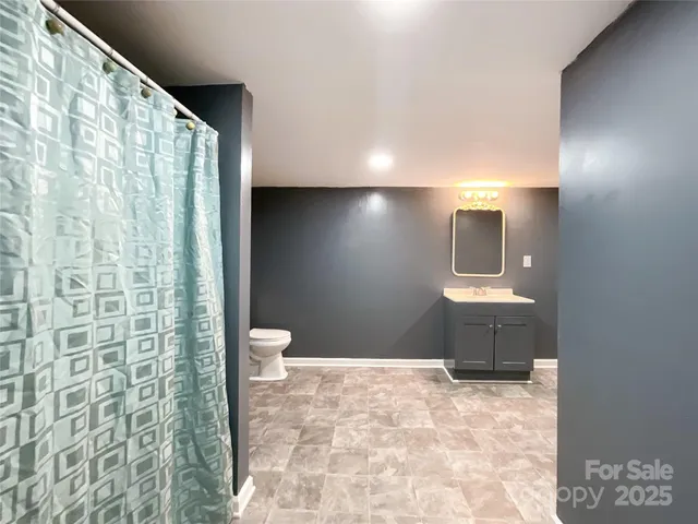 a bathroom with a granite countertop sink a toilet and shower