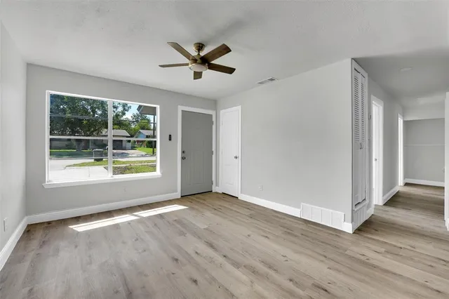 a view of an empty room with wooden floor and a window
