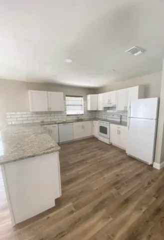 a kitchen with a refrigerator and white cabinets