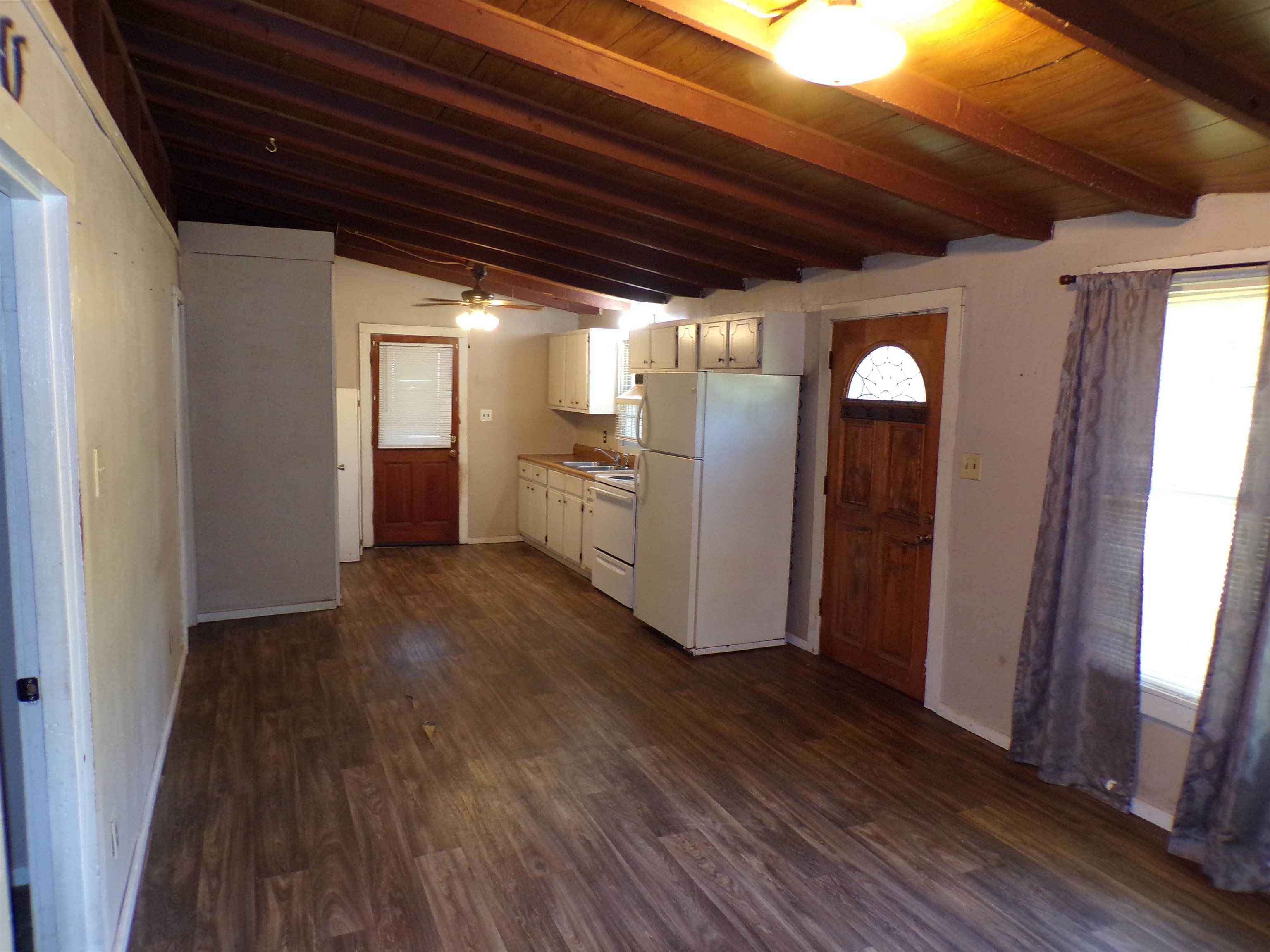 35 Cr 341 Road Iuka, MS 38852 - Photo 6 of 15 Open-concept living space featuring wood-finish flooring, exposed beam ceiling, and a kitchen with white cabinetry