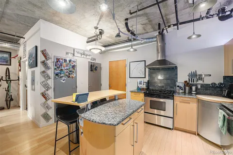 a kitchen with stainless steel appliances granite countertop a stove a refrigerator a oven with white cabinets and wooden floor