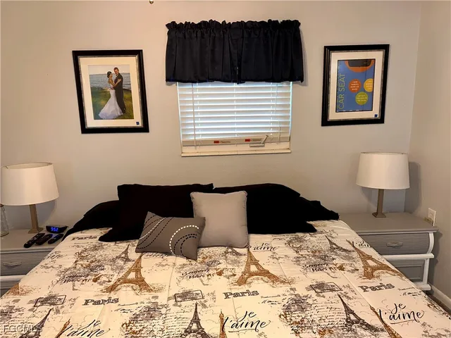 a bedroom with a bed and a lamp on dresser