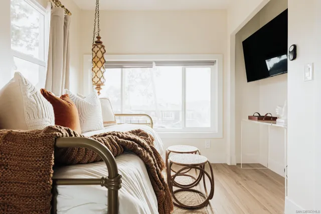a large white bed sitting in a bedroom next to a window