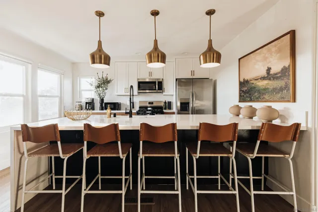 a kitchen with a sink a island and windows in it