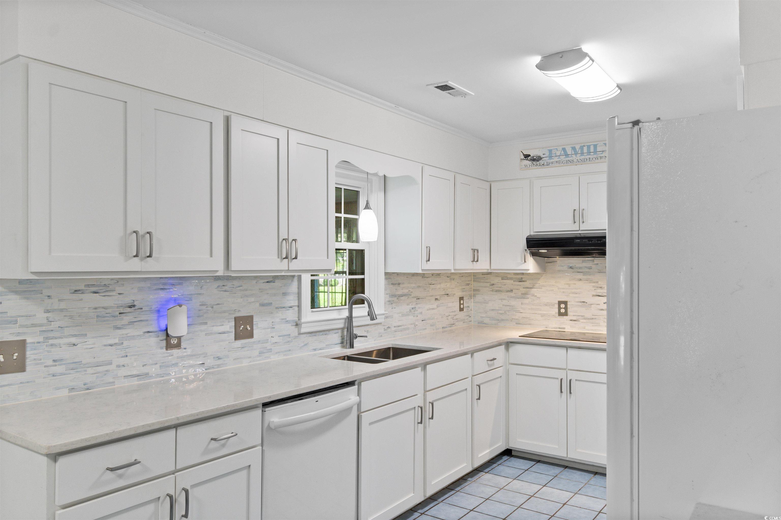 814 2nd Avenue Georgetown, SC 29440 - Photo 12 of 39 Kitchen featuring white appliances, white cabinetry, tasteful backsplash, light tile patterned flooring, and crown molding