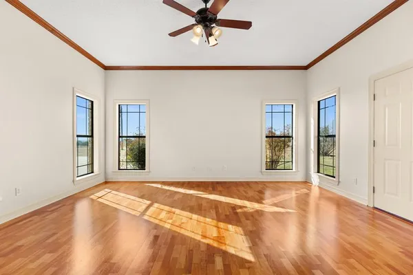 a view of an empty room with window and wooden floor
