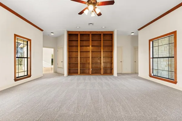 an empty room with windows closet and chandelier fan