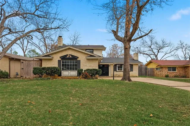 a view of a yard in front of a house with large trees