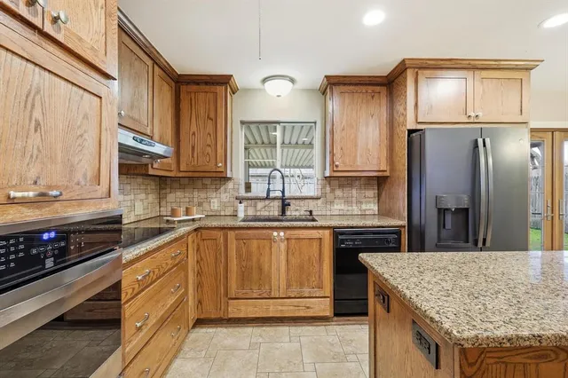 a kitchen with stainless steel appliances granite countertop wooden cabinets a stove top oven and granite counter tops