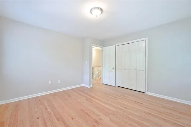 an empty room with wooden floor chandelier fan and windows