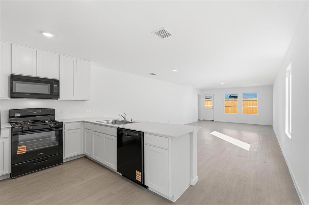 3919 Selawik Street Sherman, TX 75090 - Photo 19 of 21 a kitchen with stainless steel appliances granite countertop a stove and a sink
