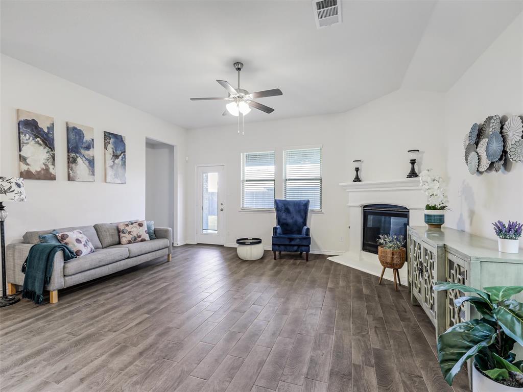 3024 Meredith Lane Forney, TX 75126 - Photo 6 of 29 Spacious living area featuring wood-finish flooring, a ceiling fan, and a fireplace with a white mantel
