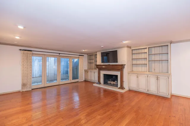 a view of an empty room with wooden floor fireplace and a window