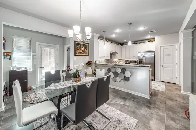 a kitchen with stainless steel appliances granite countertop a sink a stove a dining table and chairs