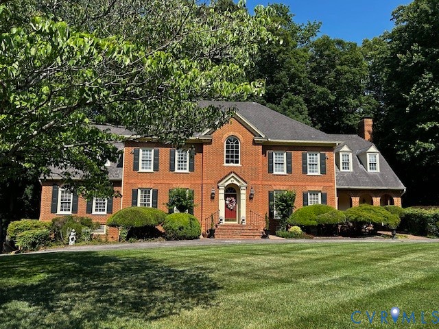 a front view of a house with a yard and green space
