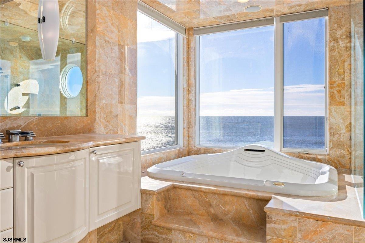 9 Point Drive Longport, NJ 08403 - Photo 28 of 38 a bathroom with a granite countertop sink and a large mirror next to a window