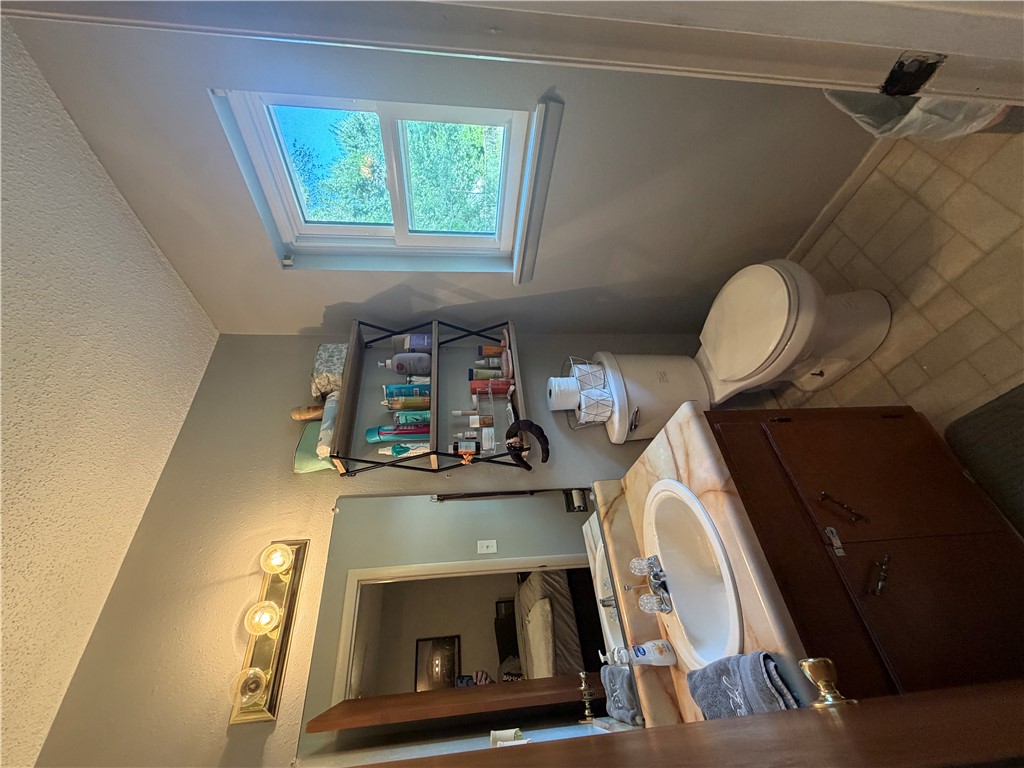 295 Hornet Estate Road London, AR 72847 - Photo 10 of 17 Bathroom featuring a single-sink vanity with a light-toned countertop, a mounted mirror, and a window providing natural illumination