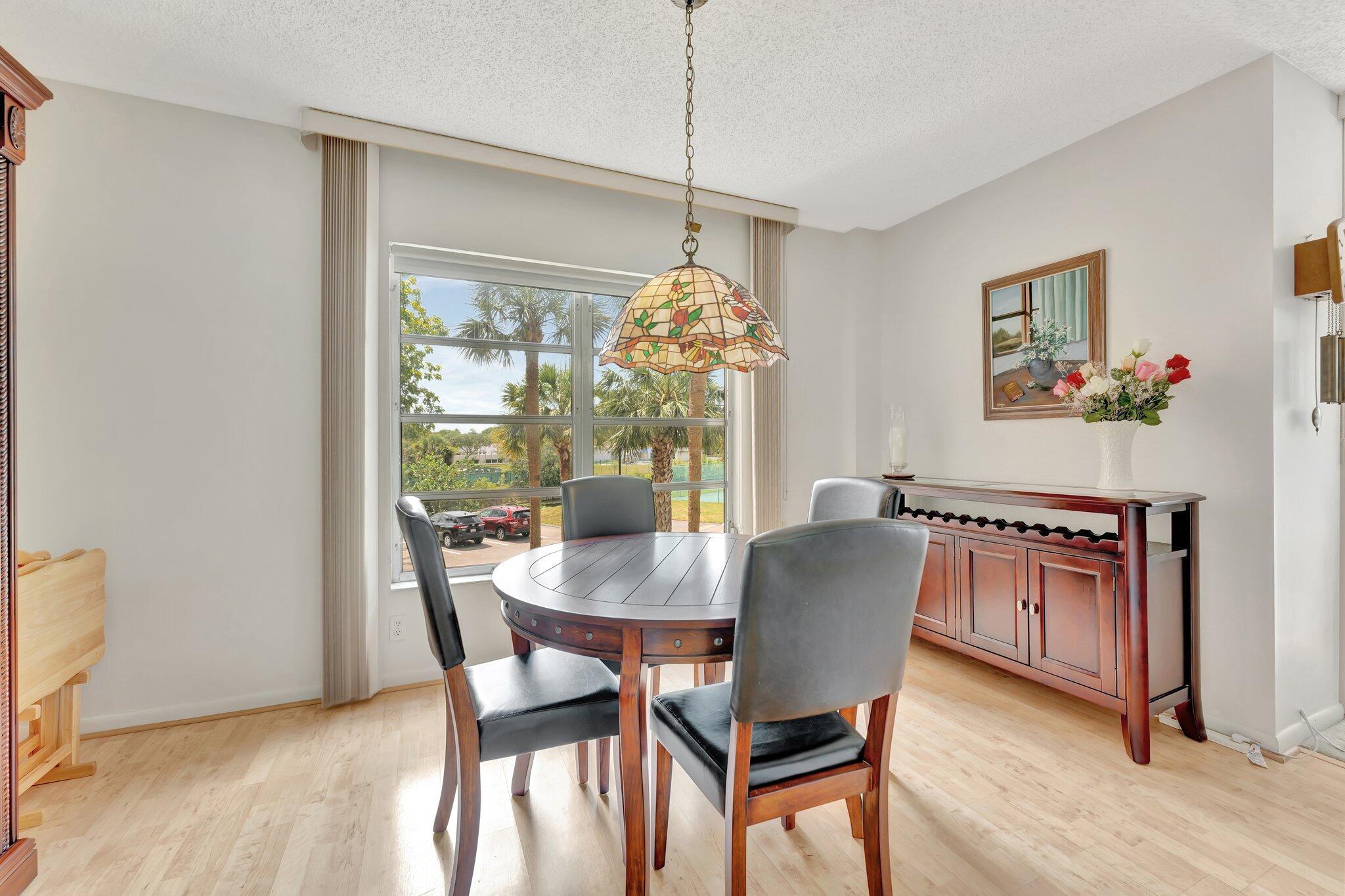 10777 West Sample Road, Unit 207 Coral Springs, FL 33065 - Photo 11 of 48 a dining room with furniture potted plants and wooden floor