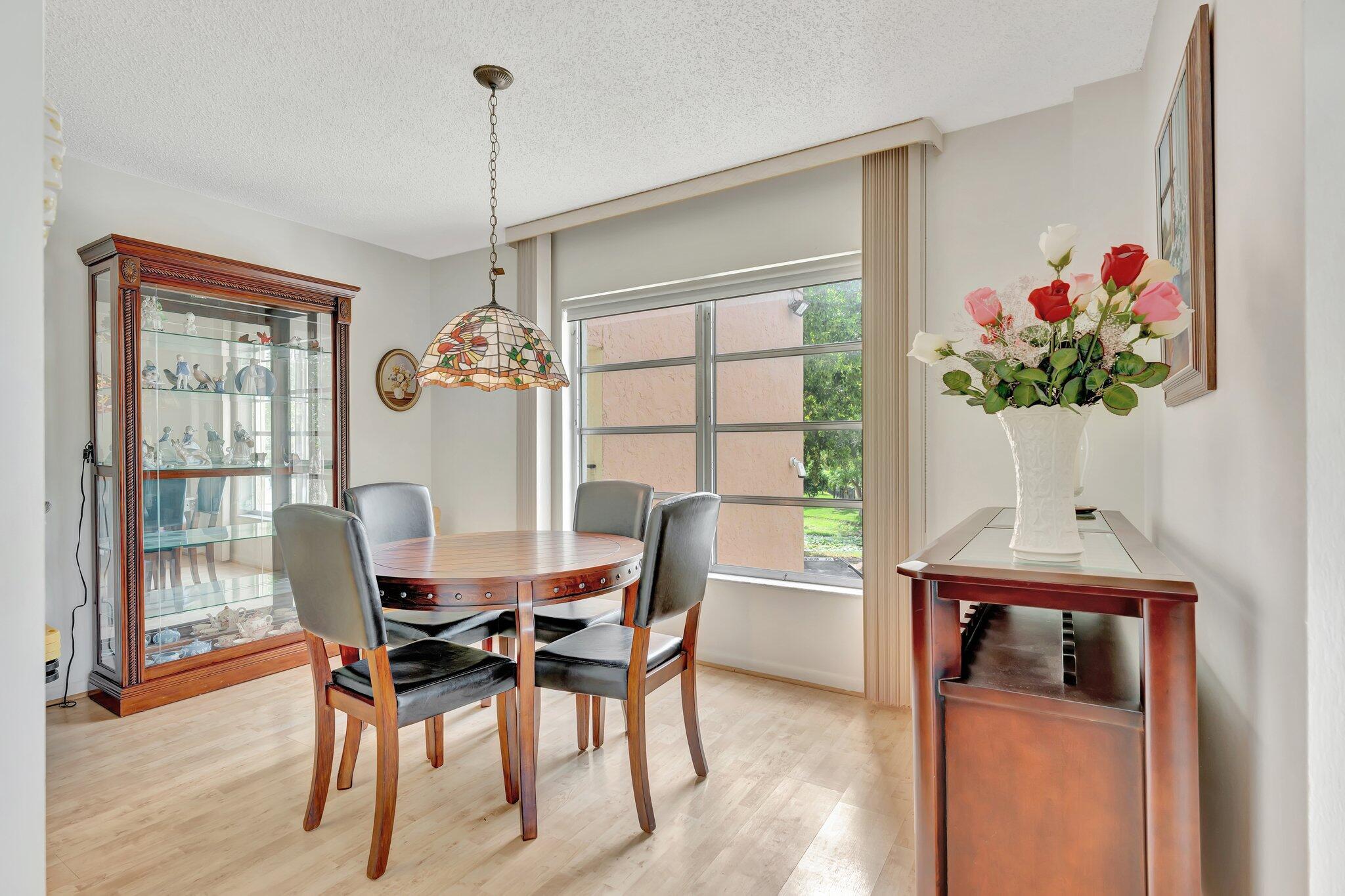 10777 West Sample Road, Unit 207 Coral Springs, FL 33065 - Photo 12 of 48 a dining room with furniture potted plants and wooden floor
