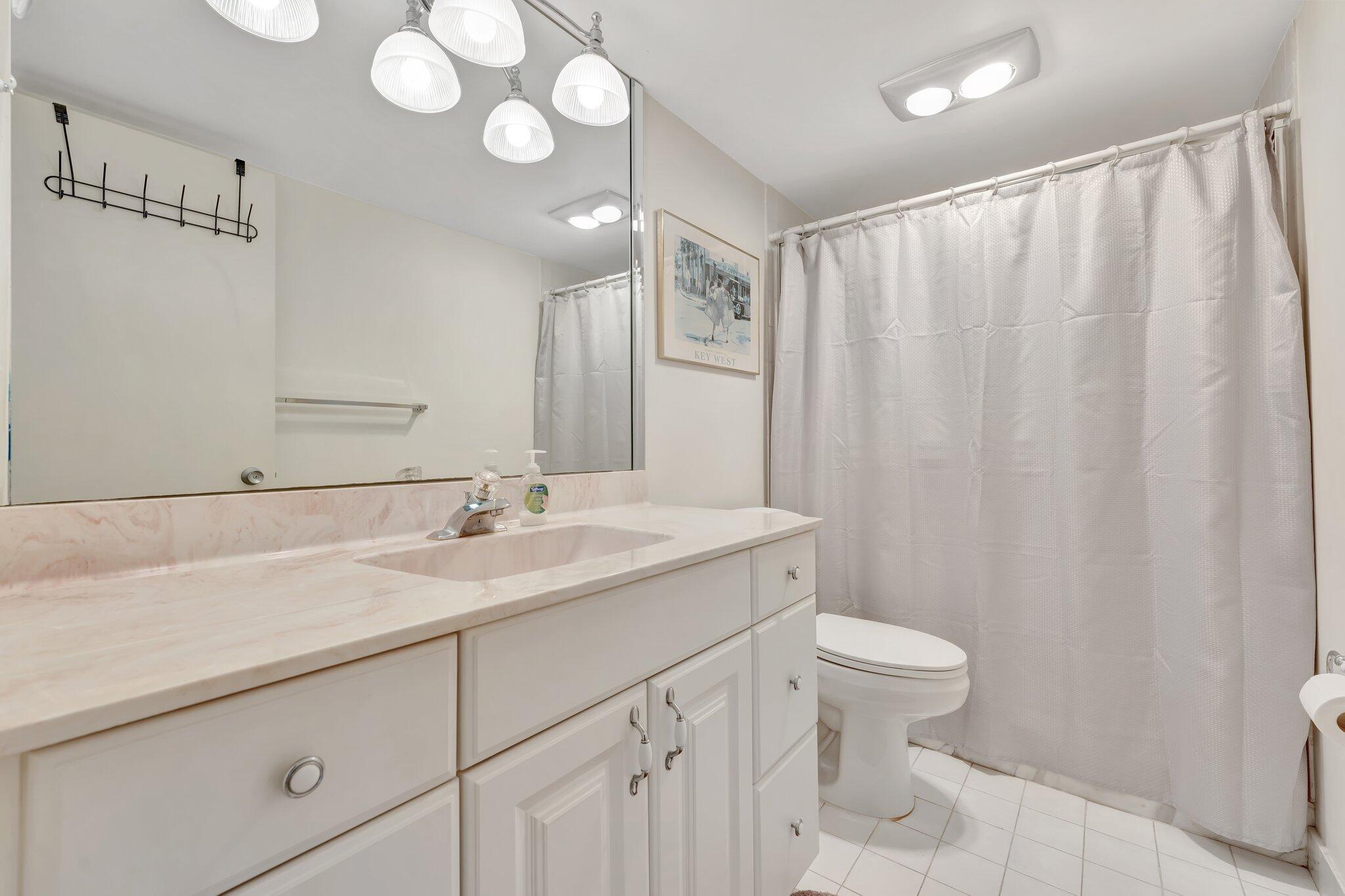 10777 West Sample Road, Unit 207 Coral Springs, FL 33065 - Photo 26 of 48 a bathroom with a sink a toilet and a mirror