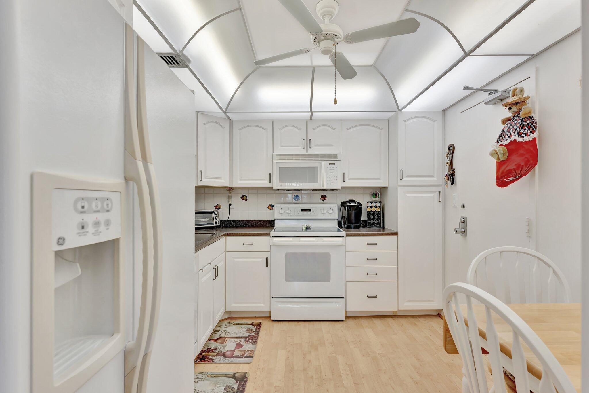 10777 West Sample Road, Unit 207 Coral Springs, FL 33065 - Photo 6 of 48 a kitchen with stainless steel appliances granite countertop a refrigerator a stove a sink dishwasher and white cabinets with wooden floor