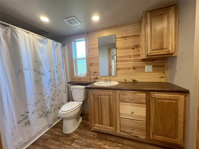 a bathroom with a granite countertop sink a toilet a mirror and shower
