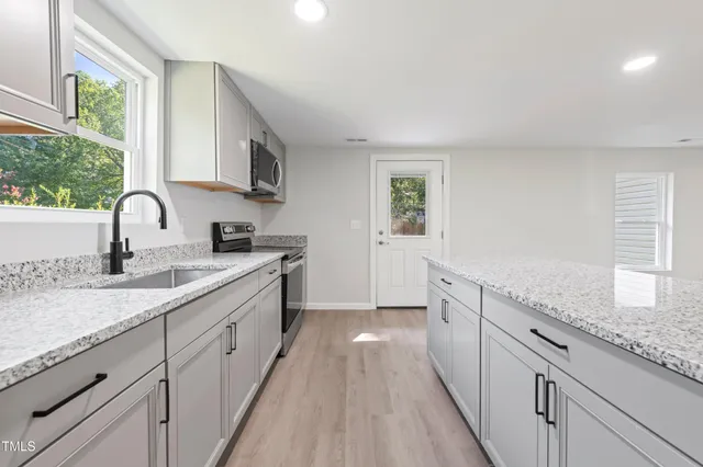 a kitchen with stainless steel appliances granite countertop a refrigerator a stove a sink a microwave and wooden cabinets