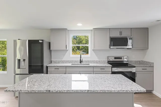 a kitchen with granite countertop a sink dishwasher stove and cabinets