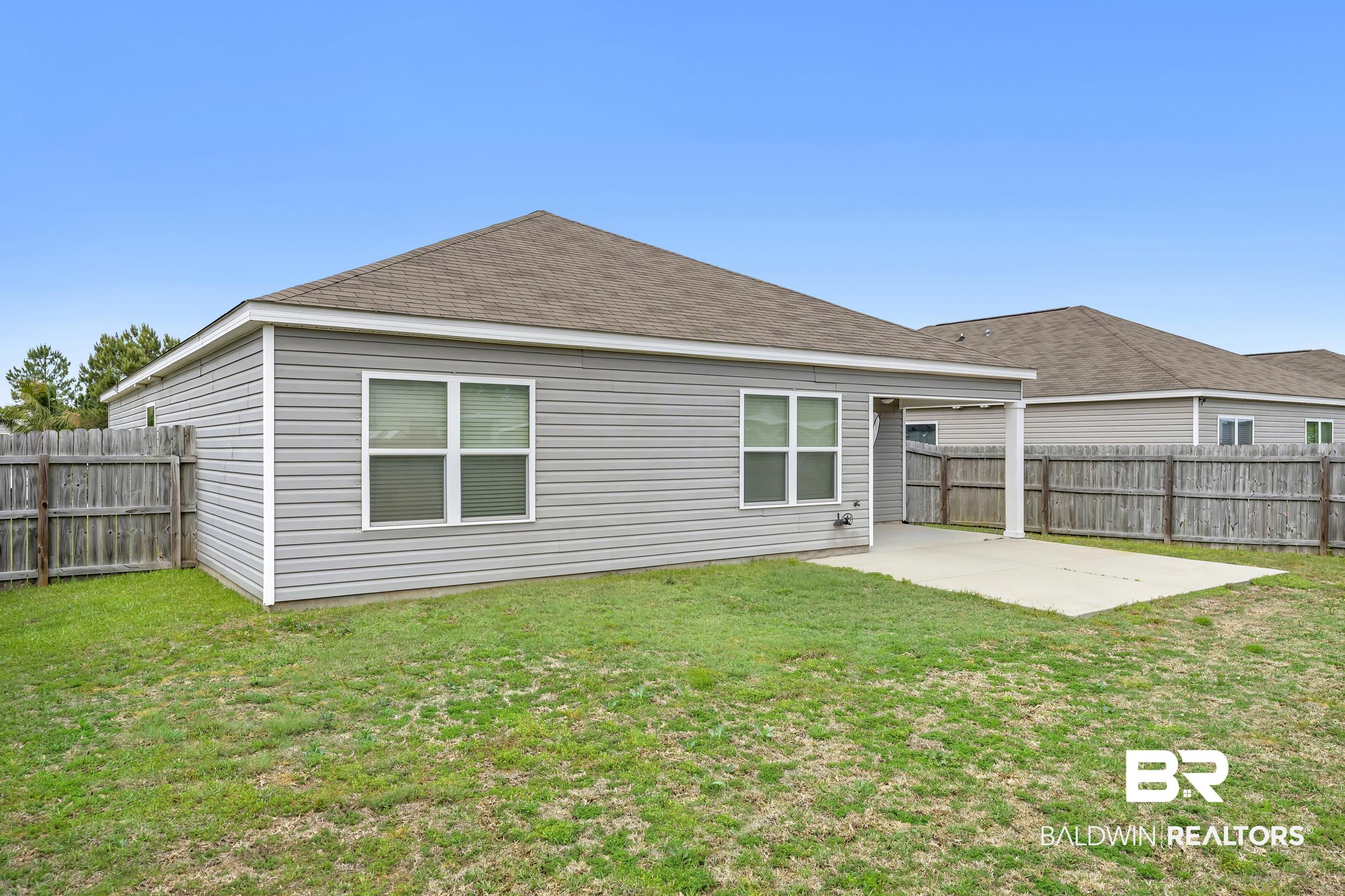 17344 Harding Drive Foley, AL 36535 - Photo 30 of 46 Rear exterior featuring gray horizontal siding, a covered patio, and a fenced backyard