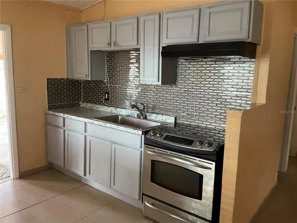 a kitchen with granite countertop a stove sink and cabinets