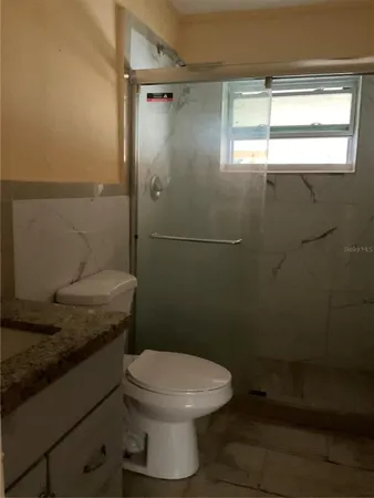 a bathroom with a granite countertop toilet a sink and a shower