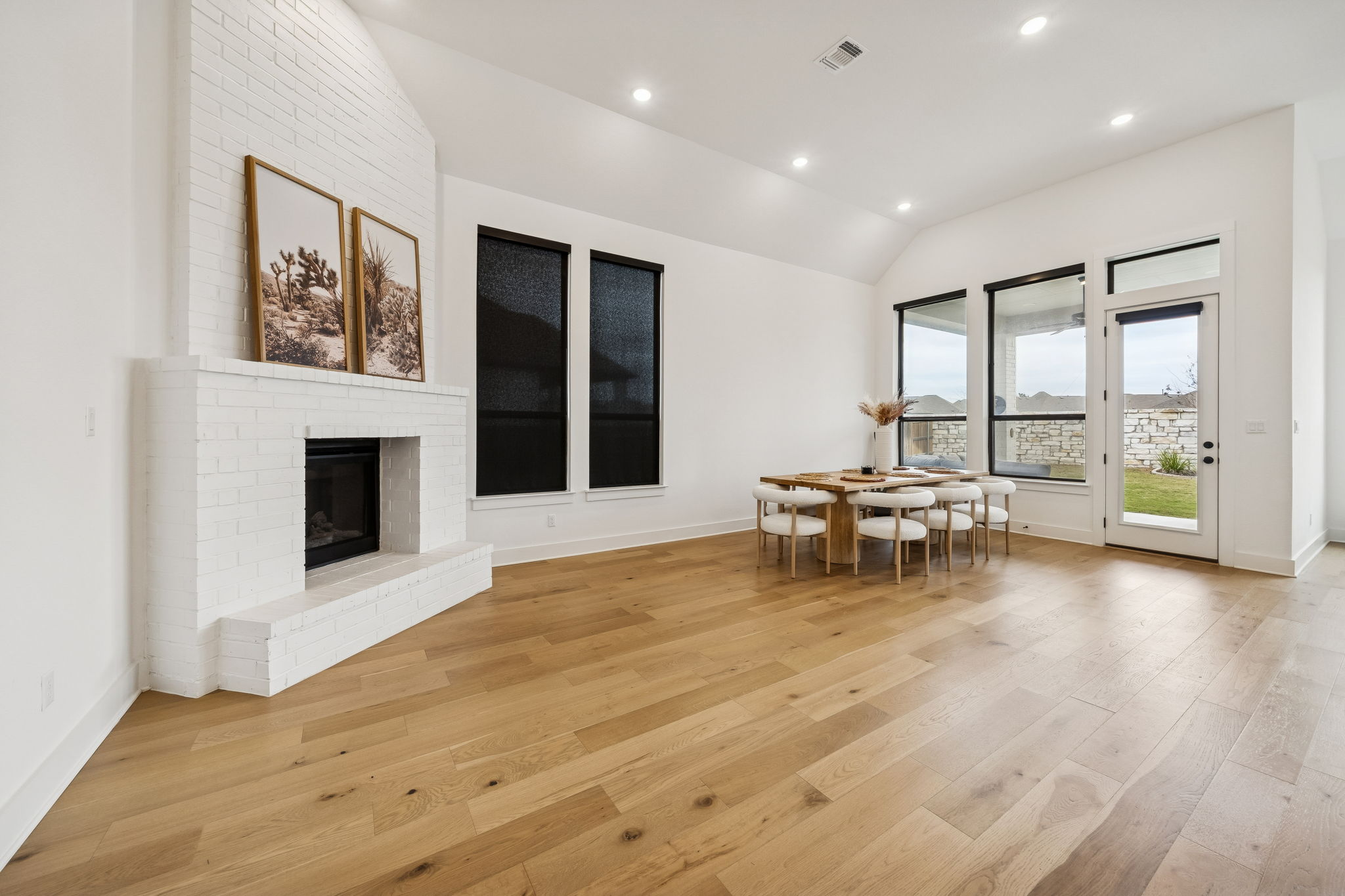269 Iron Crk Way Kyle, TX 78640 - Photo 12 of 32 Dining space with vaulted ceiling, recessed lighting, a brick fireplace, and light wood finished floors