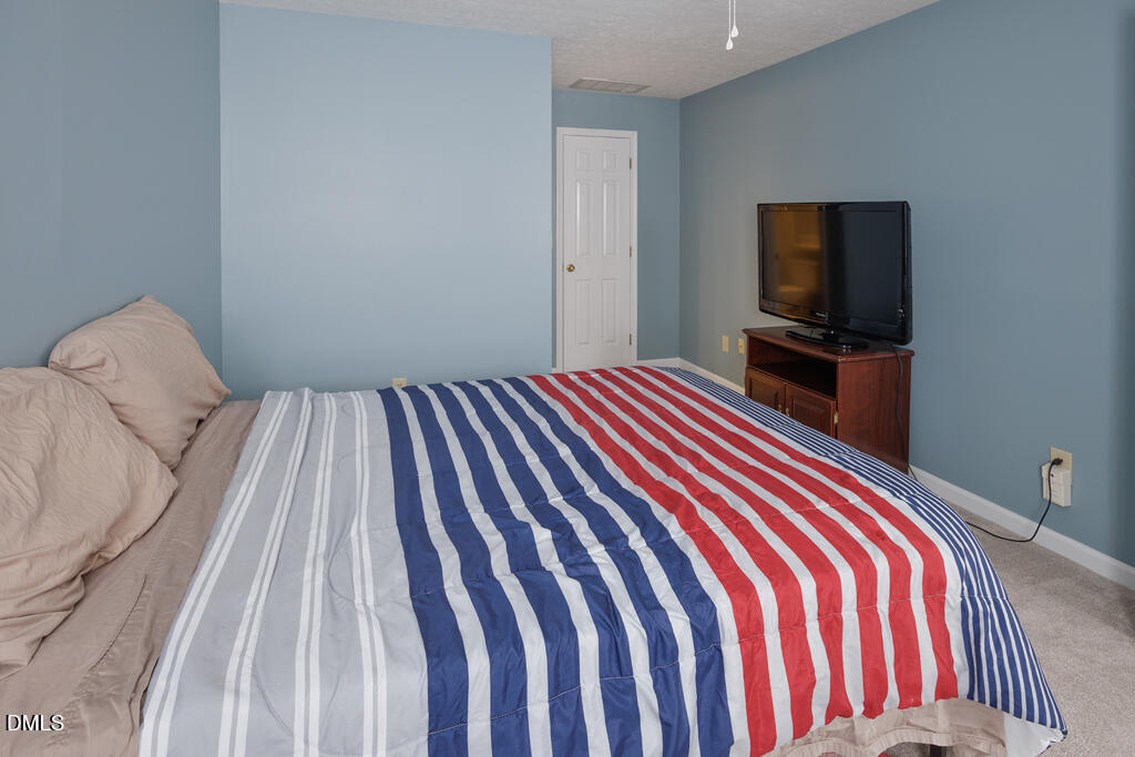 412 Oak Hollow Court Raleigh, NC 27613 - Photo 17 of 24 a bedroom with a bed and a flat screen tv