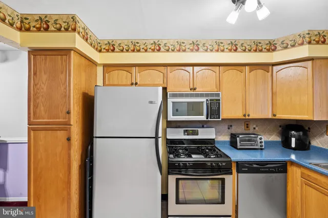 a kitchen with stainless steel appliances granite countertop a refrigerator a stove and a sink with wooden floor