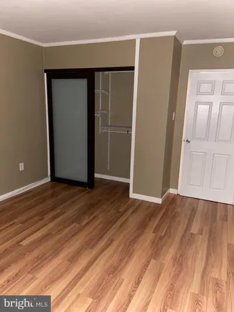 a view of an empty room with wooden floor and closet
