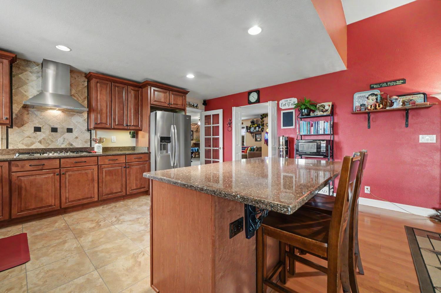 6364 Baldwin Street Valley Springs, CA 95252 - Photo 16 of 72 a kitchen with stainless steel appliances granite countertop a kitchen island a stove a dining table and chairs with wooden floor
