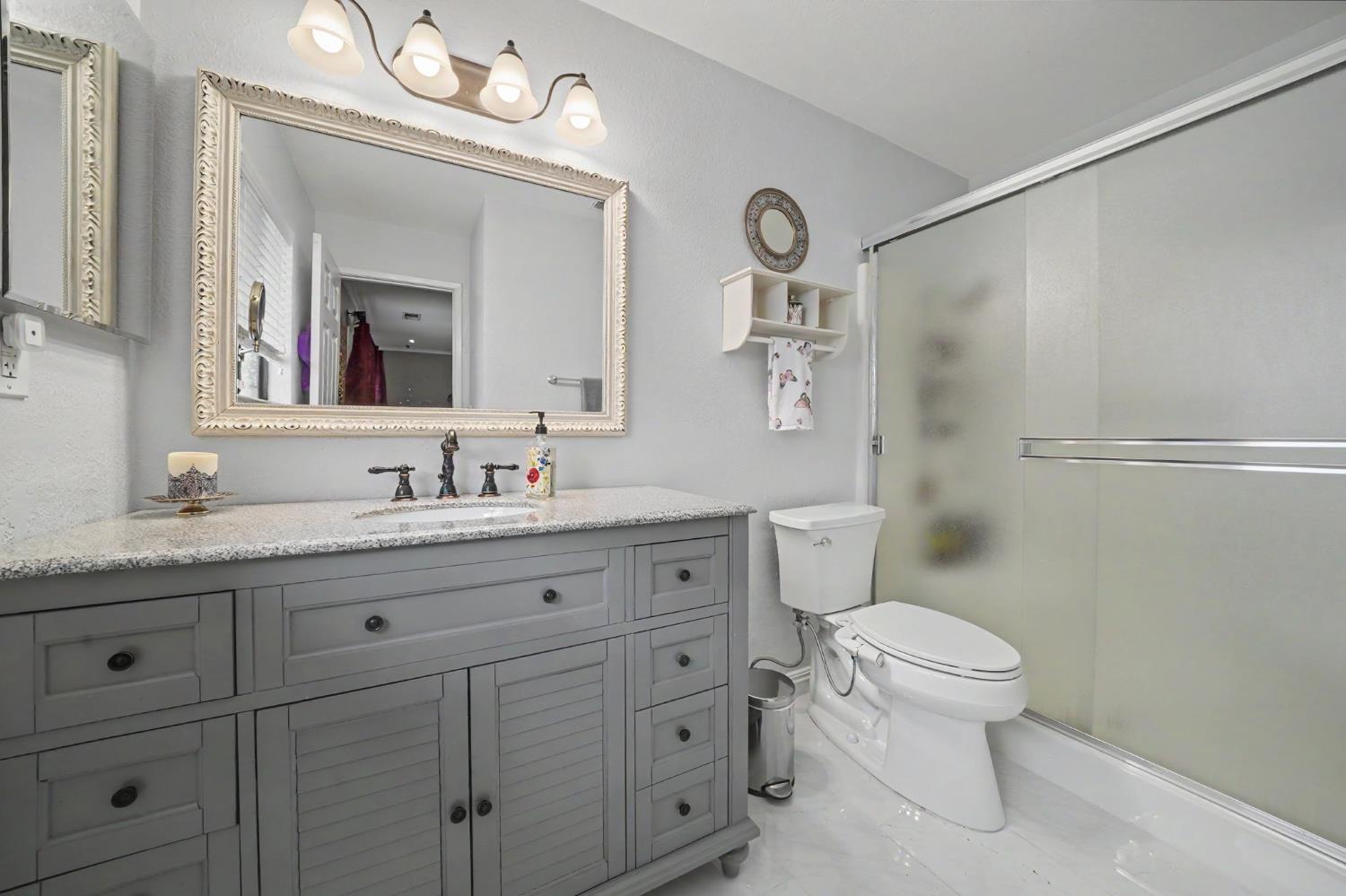 6364 Baldwin Street Valley Springs, CA 95252 - Photo 40 of 72 a bathroom with a granite countertop toilet a sink and a mirror