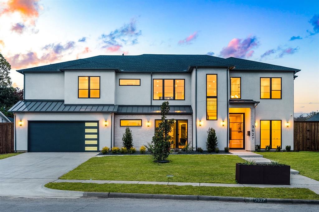 View of front of house with an attached garage, driveway, a standing seam roof, brick siding, and a metal roof