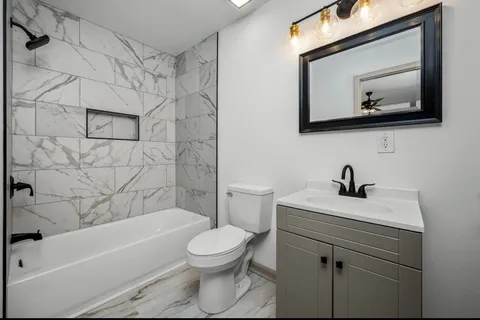 a bathroom with a toilet a sink a mirror and bathtub
