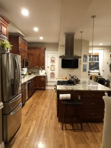 a kitchen with stainless steel appliances granite countertop a refrigerator a stove a sink a oven with a dining table and chairs