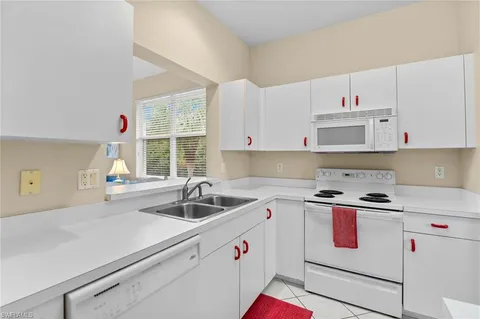 a kitchen with cabinets a sink and white appliances