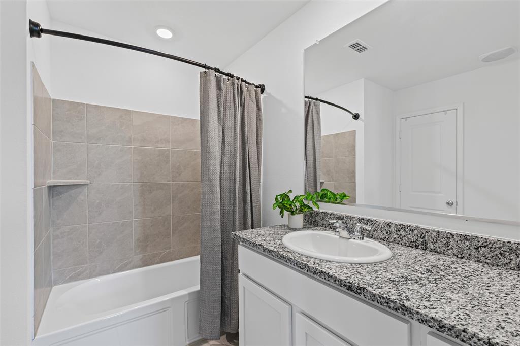 14004 Gaskin Street Pilot Point, TX 76258 - Photo 11 of 31 a bathroom with a granite countertop sink and mirror with bathtub