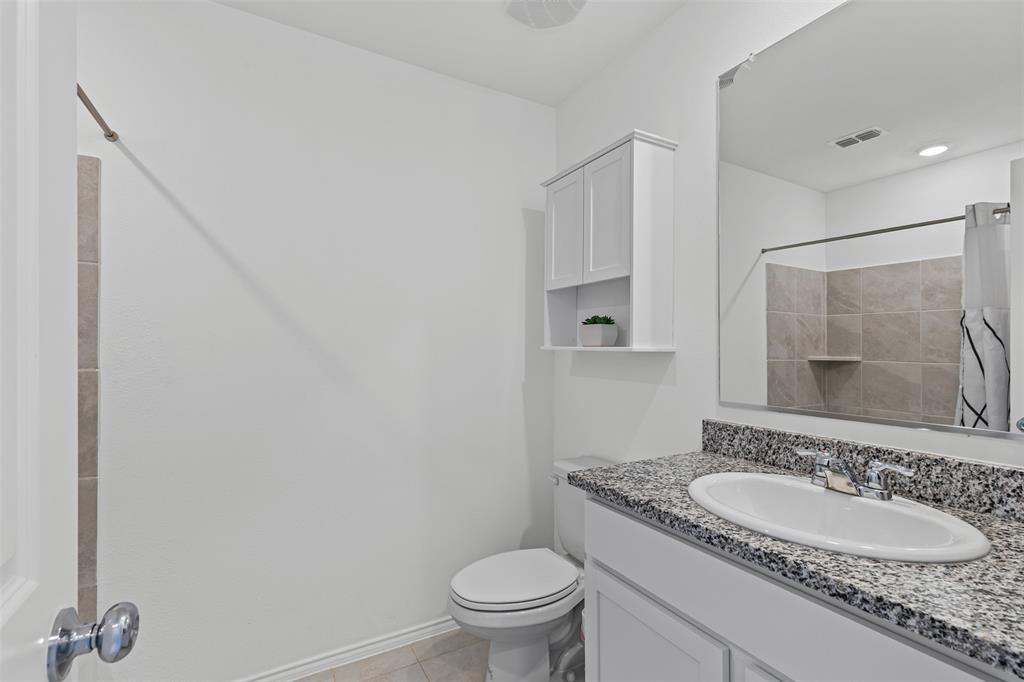 14004 Gaskin Street Pilot Point, TX 76258 - Photo 15 of 31 a bathroom with a granite countertop sink a toilet and a mirror
