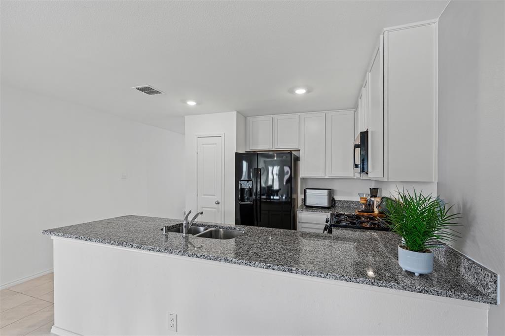 14004 Gaskin Street Pilot Point, TX 76258 - Photo 9 of 31 a kitchen with a sink and a refrigerator