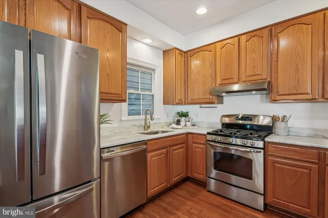 a kitchen with stainless steel appliances granite countertop a refrigerator a sink dishwasher and a stove with wooden floors