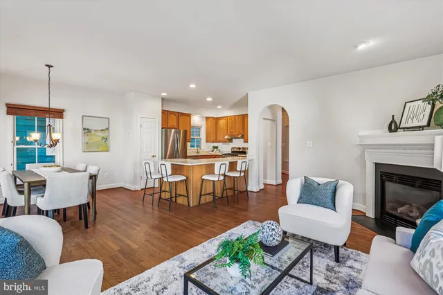 a living room with furniture a fireplace and a dining table with wooden floor